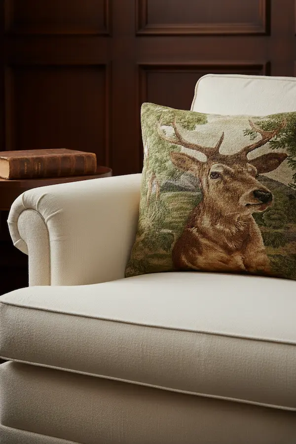 Noble Stag Tapestry Pillow styled on a cream armchair, handmade jacquard cushion with stag motif and velvet back